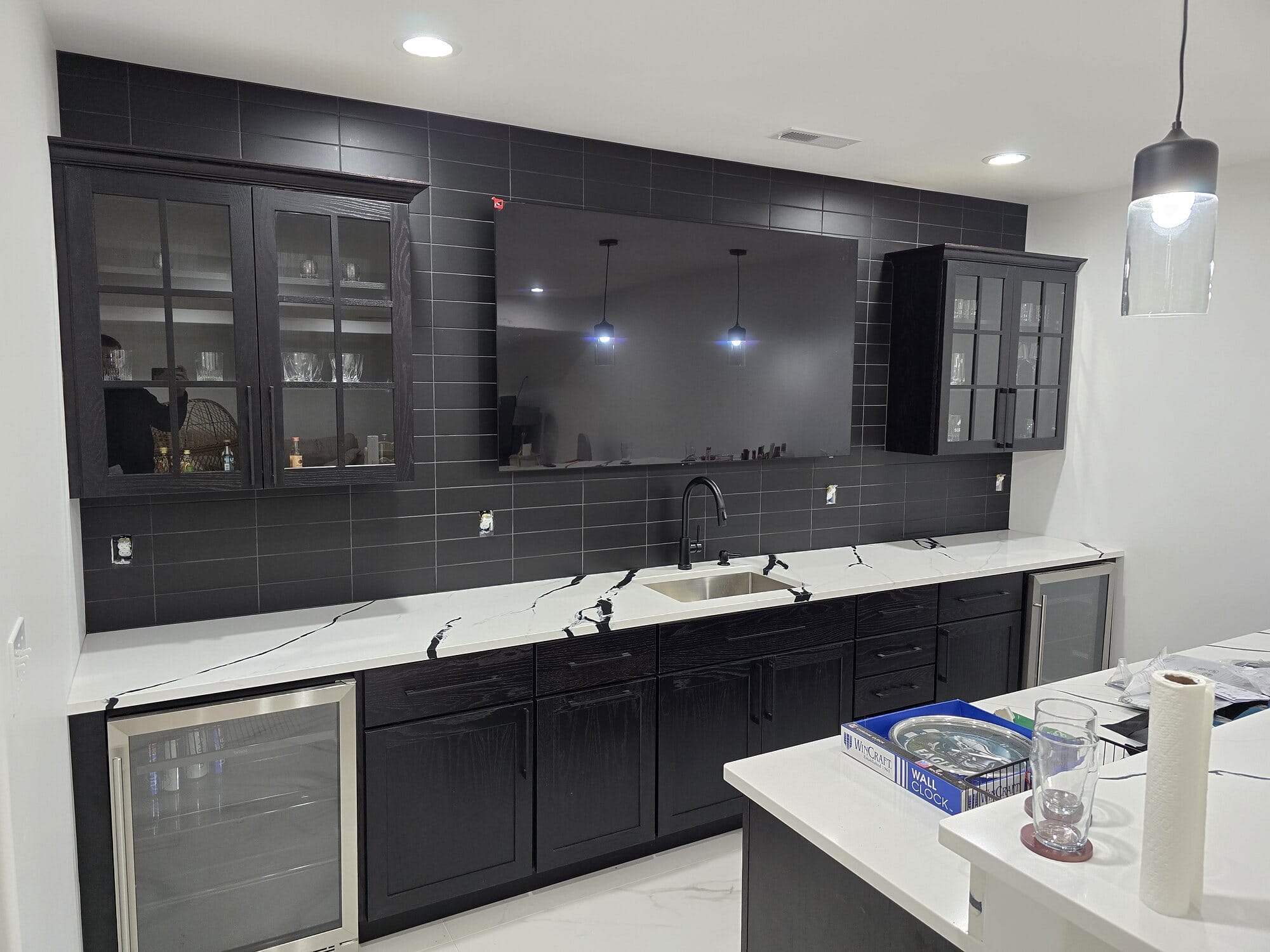 Butler's pantry and bar with dark glass-front upper cabinets, dual beverage refrigerators, prep sink, and white quartz countertops.