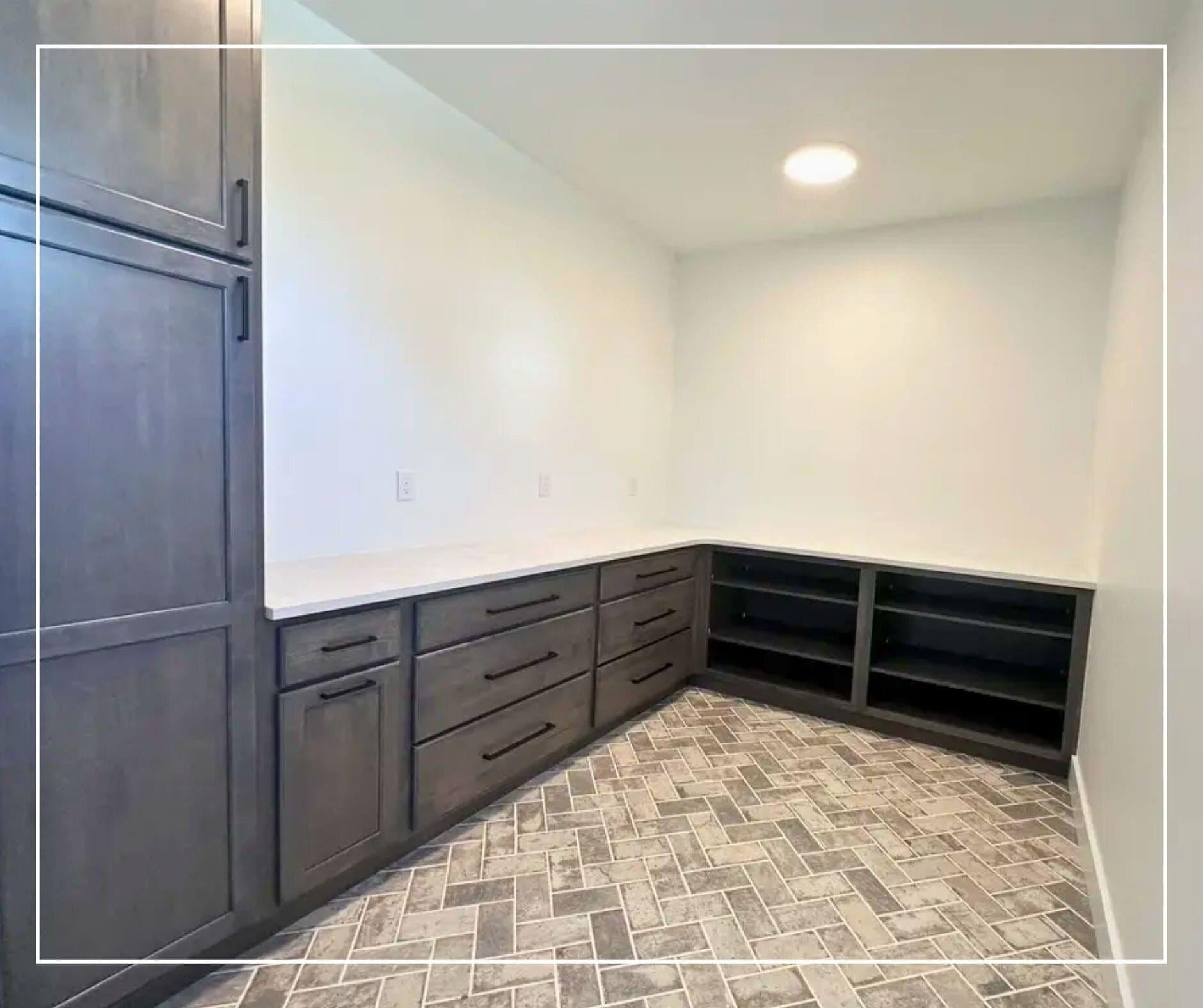 Mudroom with gray stained cabinetry, a full-length folding counter, open cubby storage, and herringbone tile flooring.