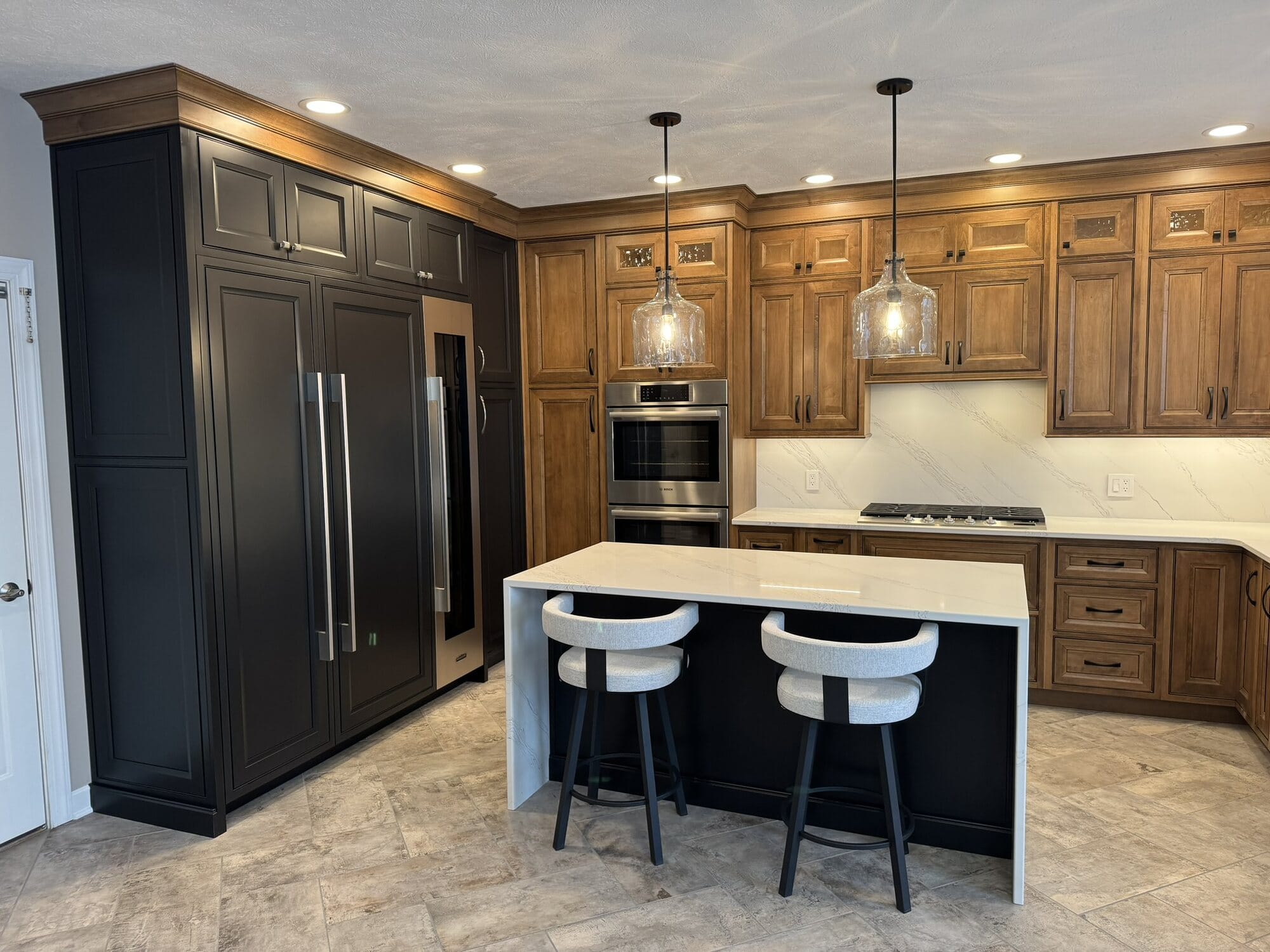 Two-tone kitchen with stained wood perimeter cabinets, a black tall-cabinet wall, quartz island, and glass pendant lighting.