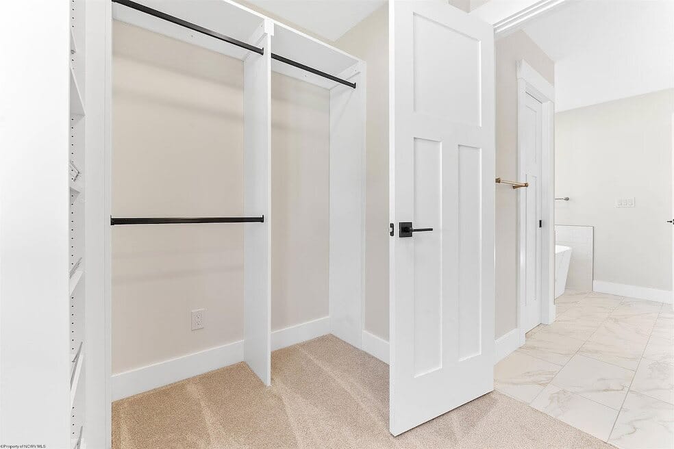 Walk-in closet corner with white built-in shelving, black hanging rods, and open storage cubbies.