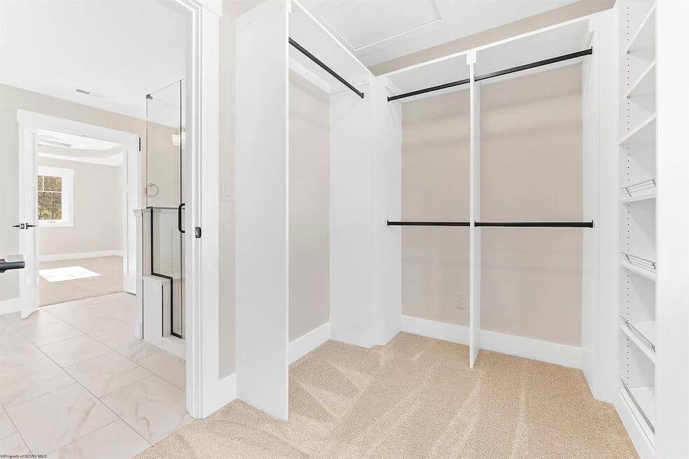 Walk-in closet with white built-in shelving, double hanging rods, and adjustable shelves for shoes and folded storage.